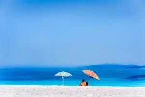 Colorful beach umbrellas crystal clear turquoise sea water paradise hidden beach. Summer concept