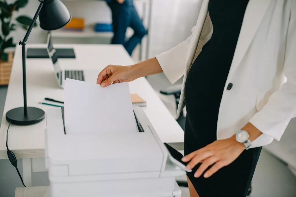partial view of pregnant businesswoman using printer in office