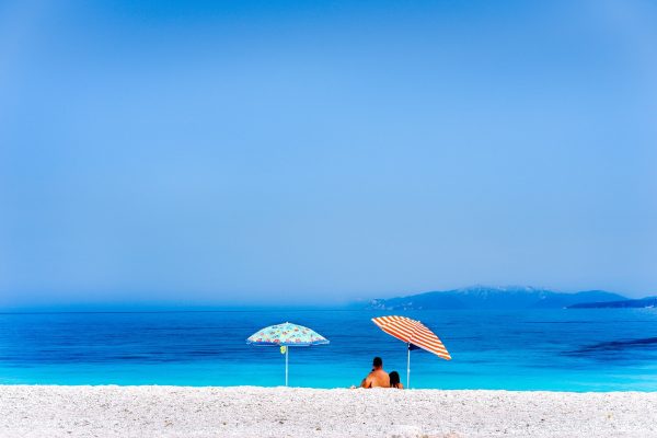 Colorful beach umbrellas crystal clear turquoise sea water paradise hidden beach. Summer concept